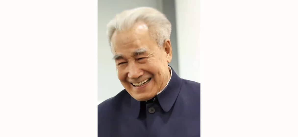 Portrait of Dr. Pang Ming, founder of Zhineng Qigong, smiling warmly in a dark traditional jacket, symbolizing his wisdom and contributions to integrative healing practices.