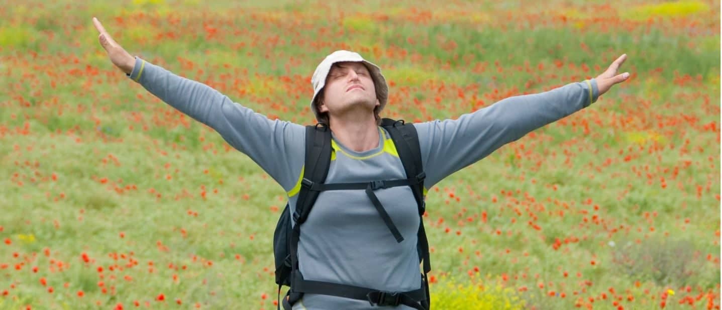 A man standing in a field with her arms outstretched.