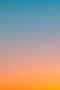 Gradient sky at sunset transitioning from warm orange and pink hues at the bottom to a calm blue at the top, creating a serene and peaceful atmosphere.