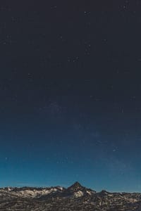 Star-filled night sky above snow-capped mountains, symbolizing tranquility, vastness, and the beauty of nature.
