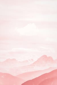 Soft pastel-toned landscape featuring distant mountain peaks and rolling hills under a cloudy sky, bathed in a gentle pink hue.