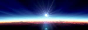 A breathtaking sunrise above the clouds, with radiant sunlight casting warm orange and pink hues across the horizon, blending into a deep blue sky.