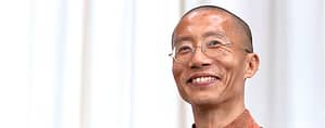 Portrait of Master Mingtong Gu smiling warmly, embodying the wisdom and energy of Wisdom Healing Qigong, with a bright, serene background enhancing his presence