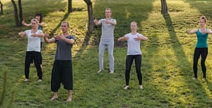 A group of people doing Qigong in a park.
