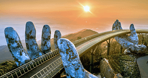 The Golden Bridge in Vietnam, held aloft by two giant stone hands, at sunrise. This iconic bridge symbolizes strength and support, mirroring themes of self-love and spirituality in Wisdom Healing Qigong. The warm sunlight bathing the scene enhances feelings of health and well-being, capturing a moment of peace and contemplation.