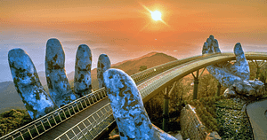 The Golden Bridge in Vietnam, held aloft by two giant stone hands, at sunrise. This iconic bridge symbolizes strength and support, mirroring themes of self-love and spirituality in Wisdom Healing Qigong. The warm sunlight bathing the scene enhances feelings of health and well-being, capturing a moment of peace and contemplation.