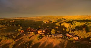 An aerial view of The Chi Center at sunset, showcasing the expansive landscape, adobe-style buildings, and natural beauty of the surrounding New Mexico terrain.