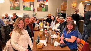 A group of smiling people gathered around a dining table, enjoying a warm and cheerful meal in a cozy restaurant setting.
