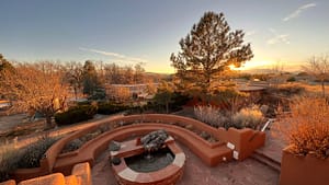 serene sunset view of The Chi Center's peaceful patio, featuring a terraced fountain, vibrant vegetation, and stunning distant mountains in Galisteo, New Mexico.