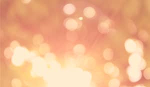 Soft abstract background with warm peach and golden hues, featuring gentle bokeh light circles and a dreamy, blurred texture.