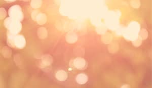 Soft abstract background with warm peach and golden hues, featuring gentle bokeh light circles and a dreamy, blurred texture.