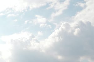 Soft, fluffy white clouds scattered across a serene blue sky.