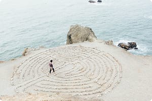 A man standing in the middle of a maze by the ocean.