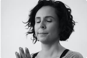 A woman holding her hands together in Qigong practice.