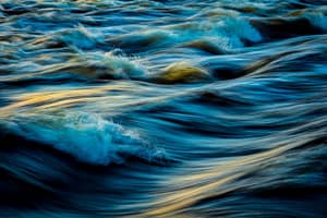 Flowing water with soft ripples and golden light reflections, symbolizing movement, serenity, and natural harmony.