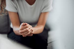 Woman with clasped hands channeling inner strength to heal from trauma.