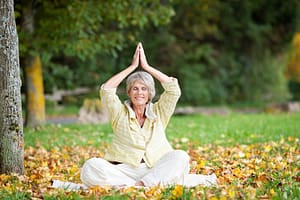 A woman practicing Qigong in a serene park, surrounded by fallen autumn leaves, embodying the essence of Life Mastery.