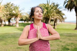 Woman practicing Qigong in a serene park with palm trees, embodying life mastery through Accepting the Past and Appreciating the Present.