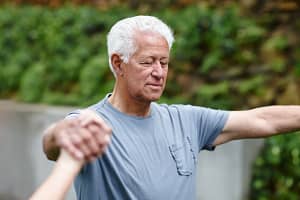 Man with eyes closed practicing Qigong, focusing on 7 Weeks of Sound Healing, in an outdoor setting, connecting deeply with movement and breath.