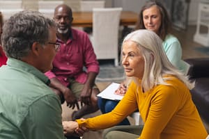 Engaged group of diverse adults participating in a meaningful conversation during a support or discussion circle in a cozy indoor setting.