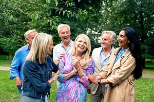 Group of diverse, joyful seniors enjoying an outdoor gathering, radiating connection, laughter, and a sense of community in a lush park setting.