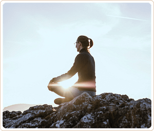 A serene image of a person meditating on a rocky hilltop at sunrise, radiating calm and mindfulness