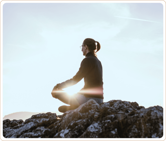 A serene image of a person meditating on a rocky hilltop at sunrise, radiating calm and mindfulness