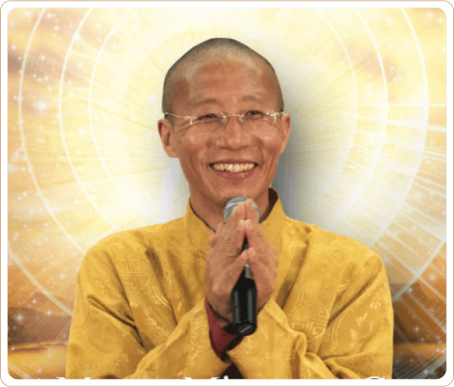 Master Mingtong Gu smiling warmly, wearing a golden robe, holding a microphone with hands in a gesture of gratitude, set against a radiant golden background symbolizing energy and light.