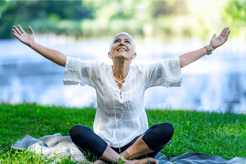 Joyful outdoor scene featuring raised hands symbolizing gratitude, freedom, and connection with nature, set against a blurred natural green background